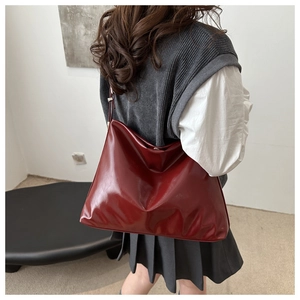 Close-up of a large dark red oil wax leather tote bag worn by a model for daily commute