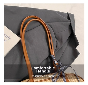 Detail of straw tote bag with brown leather handles and a blue plaid bow decoration