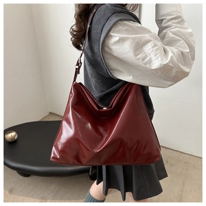 Deep red patent leather tote bag shown on model highlighting size and natural drape