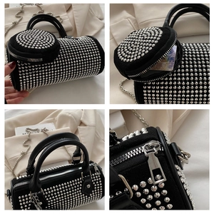 Detail view of black cylinder bag with silver studs, chain strap and round coin purse