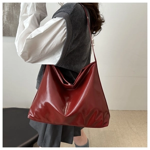 Deep red glossy faux leather tote bag worn by a model for a chic commuter style