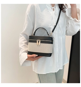 Detail of linen and leather bucket bag with gold zippers and detachable strap