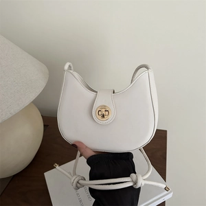 Sac hobo blanc minimaliste avec fermoir rotatif doré présenté dans un décor intérieur