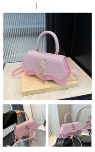 Close-up of pink rhinestone handbag with gold SS logo and elegant wave-cut flap