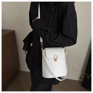Detail of white leather crossbody bag with elegant gold buckle on black outfit