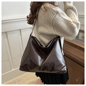 Detailed view of the large dark brown oil wax leather tote bag worn by a model