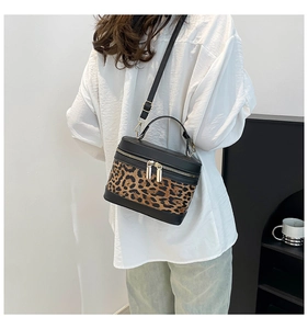 Detail of leopard print cylinder bag with gold hardware and black leather trim