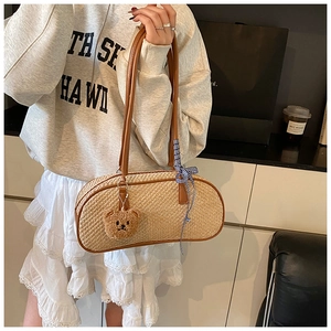 Detail of hand-woven straw shoulder bag with brown leather trim and bear pendant charm