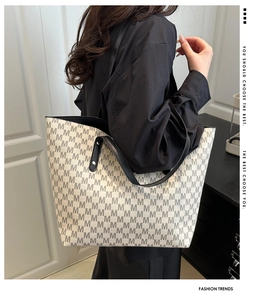 Detailed view of spacious tote bag with monogram pattern and black leather handles