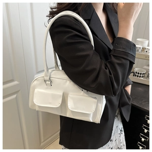 Detail of white shoulder bag featuring symmetrical front flap pockets and silver metal rings