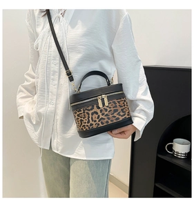 Detailed view of leopard print crossbody box bag with black leather trim and gold zippers