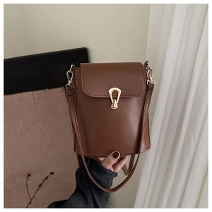 Detail of vintage brown bucket bag with gold horseshoe buckle and adjustable leather strap
