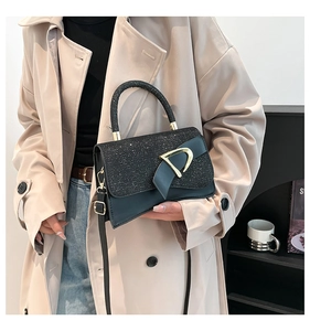 Detail of glitter stitching on black handbag with gold D-buckle and thin shoulder strap
