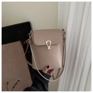 Detail of light khaki bucket bag featuring gold drop-shaped clasp and fine leather texture