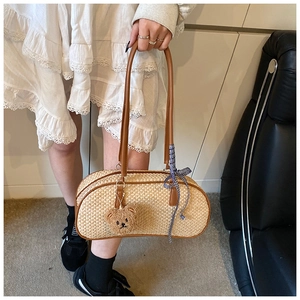 Detail of straw woven handbag with brown leather trim and cute plush bear charm