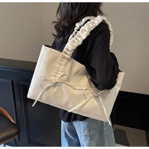 Close-up of cream white tote bag featuring bow accents and ruffled cloud shoulder straps