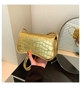 Detailed view of metallic gold crocodile embossed handbag with glossy finish and flap