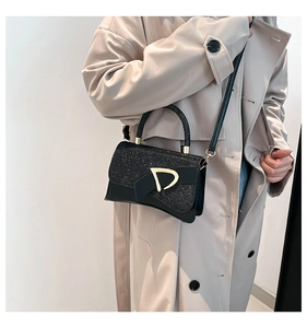Close-up of black sequined crossbody bag with gold D-buckle and bow design details