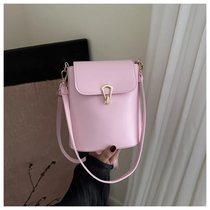 Detail of pink cylindrical crossbody bag featuring a golden horseshoe buckle and smooth leather