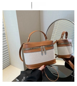 Detail view of brown leather and canvas bucket bag with dual zippers and handle