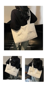 Detail of cream pleated tote bag featuring decorative bows and soft textured fabric