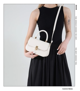 Detail of white leather shoulder bag featuring a gold metal twist lock and handle