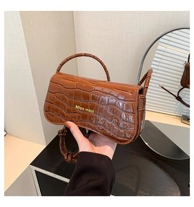 Close-up of brown crocodile pattern handbag with Miss mini gold logo and knotted strap