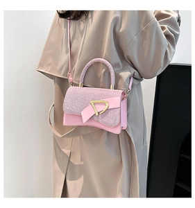 Detail of glitter pink crossbody bag with a gold D-shaped buckle on a khaki trench coat