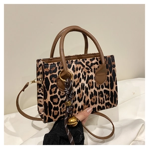 Detail of leopard print handbag featuring gold ball charm and brown faux leather strap