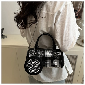 Detail of black Boston bag with silver studs and chain strap worn by a model