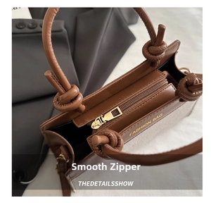 Detailed close-up of smooth metal zipper and knotted handle on caramel brown saddle bag