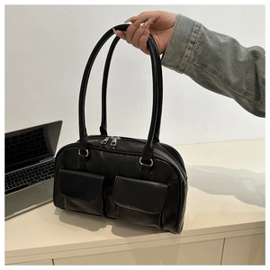 Close-up of black matte leather tote bag featuring dual front pockets and silver zippers