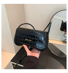 Detail of black faux crocodile leather shoulder bag featuring golden Miss mini logo