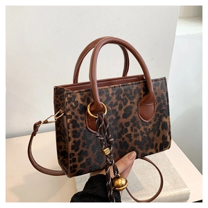 Detailed view of leopard print tote featuring a brown handle and a bell charm decoration