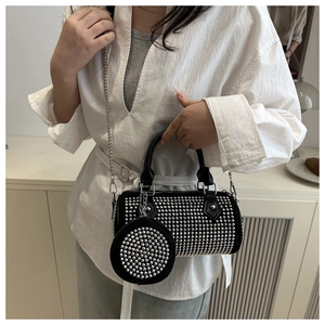 Sac cylindre noir tendance avec clous argentés et bandoulière porté par un mannequin