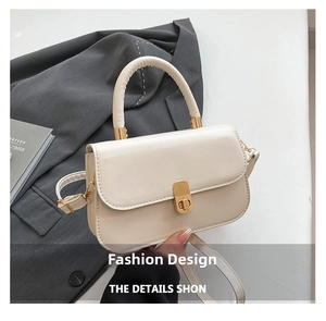 Detail view of cream PU leather handbag with gold metal hardware and textured suit background