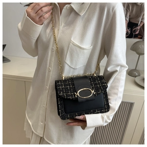 Detail der schwarzen Tweed- und Ledertasche mit großer goldener Schnalle und Kette