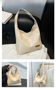 Close-up of cream PU leather tote bag with brown tag and minimalist shoulder straps