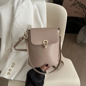 Elegant beige bucket bag with gold hardware shown on a white blazer in a chic indoor setting