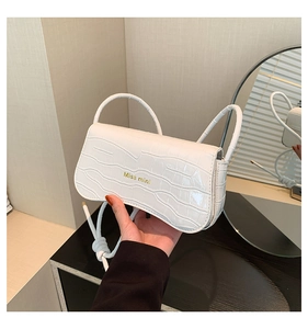 Detailed close-up of a white crocodile embossed handbag with gold Miss mini logo