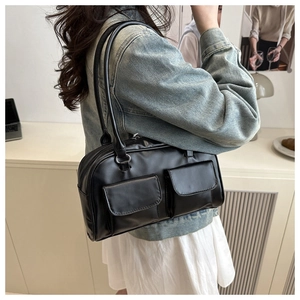 Close-up of minimalist black leather underarm bag with double front pocket design