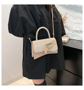 Close-up of champagne shimmering small square bag with golden triangle buckle and handle