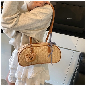 Detailed shot of beige woven shell bag with leather trim and plush bear charm