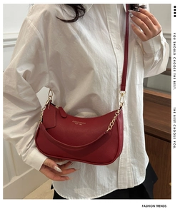Close-up of burgundy hobo bag with adjustable strap, gold chain, and lychee grain leather