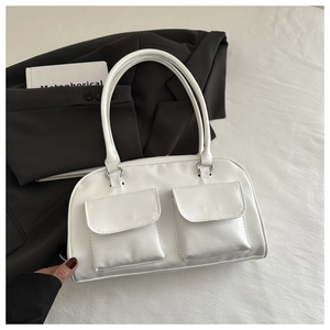 Detail of white leather shoulder bag featuring two symmetrical front flap pockets and handles