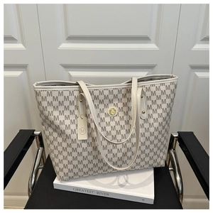 Detail der Monogramm-Tote-Bag mit M-Muster, goldenem Metall-Logo und beigen Ledergriffen