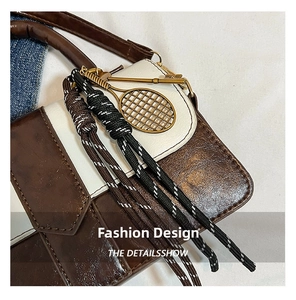 Gros plan détaillé du sac en cuir bicolore avec pendentif raquette de tennis doré