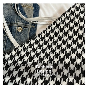 Detailed view of the houndstooth woven fabric and thin white strap on the tote bag
