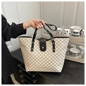 Close-up of large canvas tote bag featuring black letter prints and leather handles