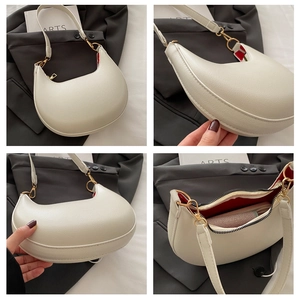 Detail der weißen Halbmond-Tasche mit Lychee-Lederstruktur und rotem Innenfutter